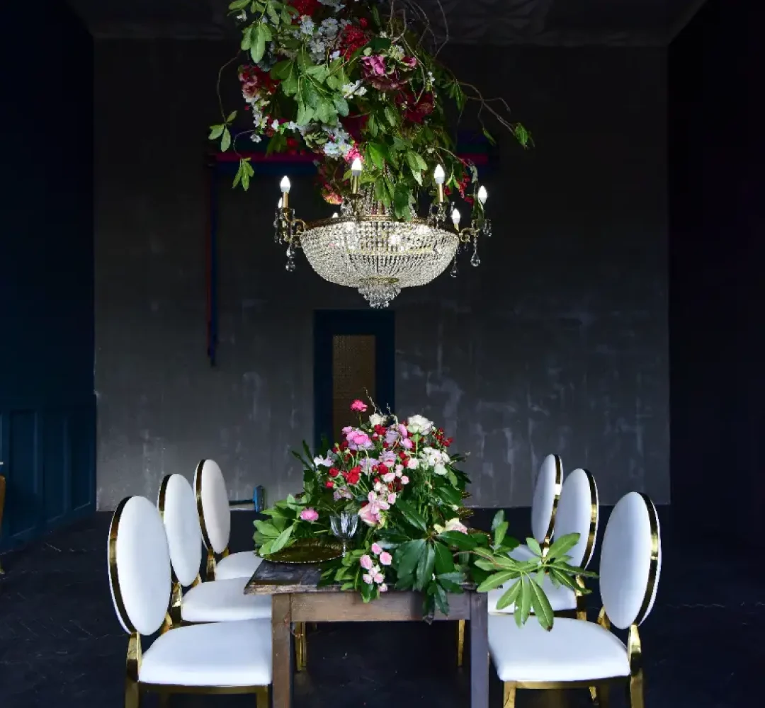 rich-christal-chandelier-hangs-dinner-table-with-red-roses-greenery